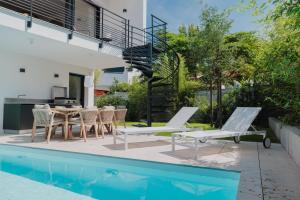 een patio met een tafel en stoelen naast een zwembad bij Villa Cordouan avec piscine en bord de mer in Royan