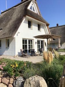 een wit huis met een patio en een parasol bij Haffkoje - Ferienhaus mit Kamin und Sauna für 6 Personen in Pepelow