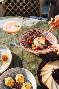 a table with plates of food and a drink at Hôtel de La Plage in Biarritz