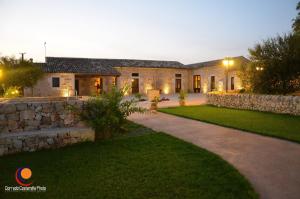 a house with a stone wall and a yard at Casale Graffetta in Ispica