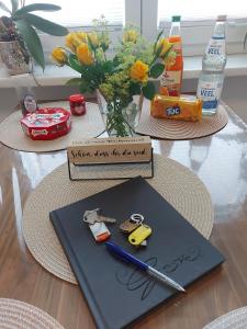 a table with a napkin with a pen and a vase of flowers at Haus An Der Marsch in Breklum