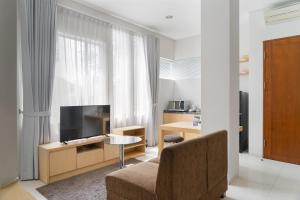 a living room with a couch and a tv and a window at Cove MK House Senopati in Jakarta