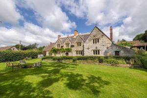 una gran casa de piedra con un patio verde en Seventeenth century luxury pad near Glastonbury, en Pilton