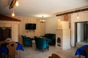 a living room with a fireplace and green chairs at Tokaji Dűlő Vendégház in Tokaj