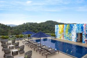 ein Pool mit Stühlen und Sonnenschirmen auf dem Dach eines Gebäudes in der Unterkunft Radisson Hotel Kandy in Kandy