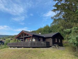 a large wooden house with a deck on a hill at Hafjell Grenda lejligheder og hytter in Hafjell