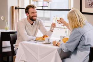 a man and woman sitting at a table drinking wine at Hotel Aazaert by WP Hotels in Blankenberge