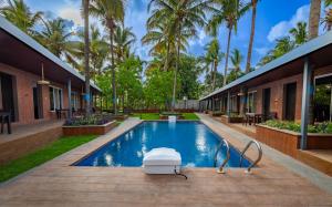 a swimming pool in a resort with palm trees at Coco Bliss By Mauli Stays in Manor