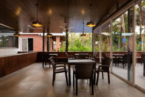 a dining room with tables and chairs and windows at Coco Bliss By Mauli Stays in Manor
