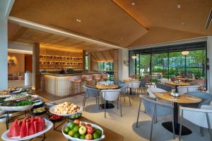 罗勇Hilton Garden Inn Rayong的餐厅设有桌椅,餐桌上备有水果