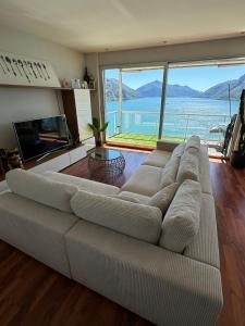 un sofá grande en una sala de estar con una ventana grande en Attico con vista panoramica sul lago - due camere, en Lugano
