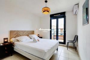 ein Schlafzimmer mit einem großen weißen Bett und einem Fenster in der Unterkunft Leu Ty Kosy - T3 en plein centre-ville - Saint-Leu in Saint-Leu