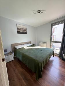 a bedroom with a large bed with a green blanket at Margas Golf Apartment 2 in Sabiñánigo +18 photos