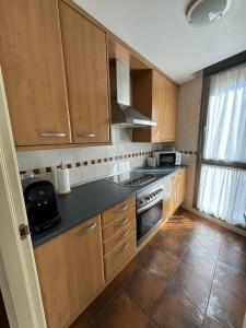 a kitchen with wooden cabinets and a sink and a stove at Margas Golf Apartment 2 in Sabiñánigo