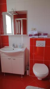 a red and white bathroom with a toilet and a sink at Apartments Tomić in Vodice
