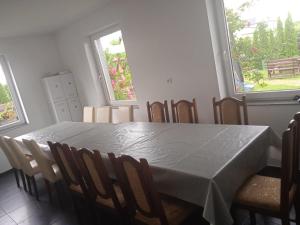 a dining room with a table and chairs and two windows at Willa Rosa - Dom dla 20 osób z jacuzzi i sauną ogrodową Kaszuby in Bukowina