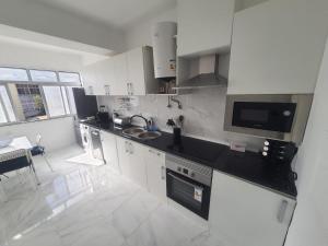 a kitchen with white cabinets and black counter tops at Odivelas Home in Odivelas