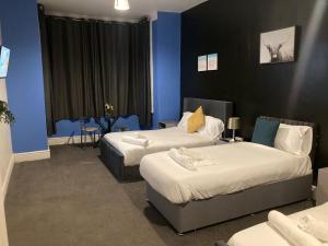 two beds in a room with blue walls at North Coast Hotel in Blackpool