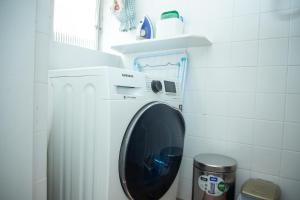 a washing machine in a bathroom with a trash can at Entre Parque Moinhos e Country Club POA ZG6320 in Porto Alegre