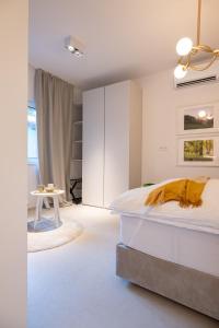 a white bedroom with a bed and a table at Trubarjeva City apartments in Ljubljana