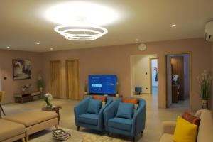 a living room with blue chairs and a large screen at Eden Kolwezi in Kolwezi