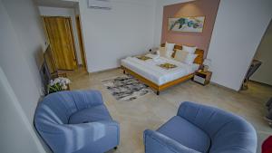 un soggiorno con un letto e due sedie di Eden Kolwezi a Kolwezi Altre 5 foto