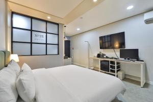 a bedroom with a large white bed and a television at No25 Samcheonpo in Sacheon