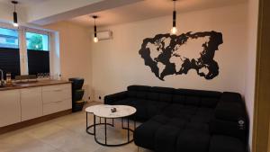 Ein Wohnzimmer mit einem schwarzen Sofa und einer Landkarte an der Wand in der Unterkunft Maestro ONE in Tychy