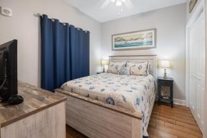a bedroom with a bed with blue curtains and a tv at Harbour Pointe 605 By Pkrm in Perdido Key +32 photos