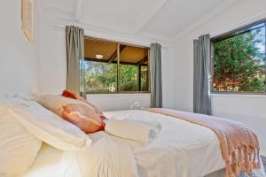 a bedroom with a bed with white sheets and windows at Ashwood Alpine House in Bright +38 photos