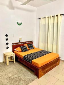 GodomèにあるYann Guest houseのベッドルーム1室(オレンジ色の掛け布団付きのベッド1台付)