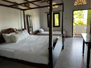 a bedroom with two beds and a table and a bed at Boomerang Una With Free Scooter Bike in Unawatuna
