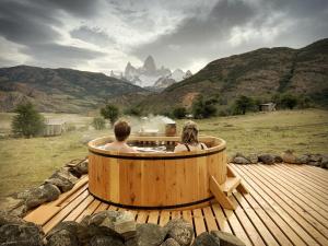 a man and woman sitting in a hot tub on a deck at Estancia Bonanza Patagonian Lodge Experience in El Chalten