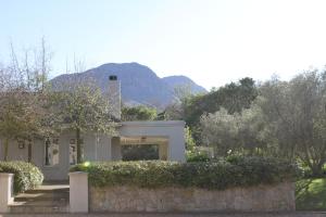a house with a stone wall in front at Jakaranda Cottage in Somerset West