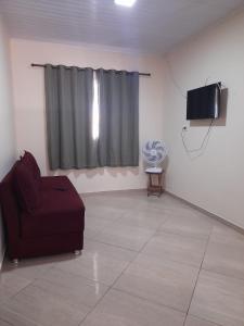 un salon avec un canapé rouge et une télévision dans l'établissement Casa de férias luar do prado, à Prado