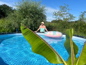 a woman in a hat is in a pool with alatable raft at Weberhof-Münster Glamping in Münster