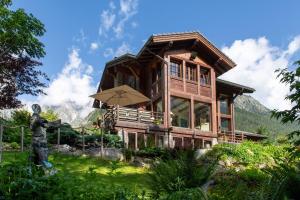 a large wooden house with a statue in front of it at Studio Cinq Moutons in Orsières