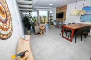 a living room with a table and a wooden duck on a surfboard at Proa Japaratinga in Japaratinga