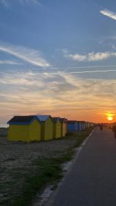 a row of beach huts with the sunset in the background at One-bedroom Apartment Sea Views in Rustington