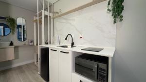 a white kitchen with a sink and a microwave at Apê Paulista Alameda Santos in São Paulo
