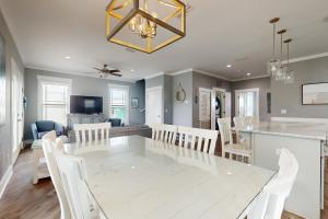 a dining room and living room with a white table and chairs at Carried Away by Meyer Vacation Rentals in Gulf Shores