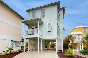 a white house with a balcony and palm trees at Carried Away by Meyer Vacation Rentals in Gulf Shores