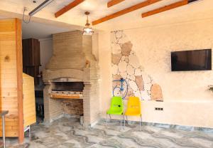 a living room with a brick fireplace with two green chairs at KareNo Hotel Tsaghkadzor in Tsaghkadzor