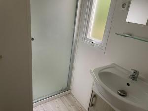 une salle de bain blanche avec un lavabo et un miroir dans l'établissement Mobilhome 29, à Bérigny