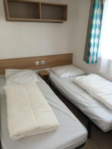 deux lits dans une chambre avec draps et oreillers blancs dans l'établissement Mobilhome 29, à Bérigny