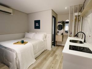 a small white bedroom with a bed and a sink at Apê Paulista Alameda Santos in São Paulo