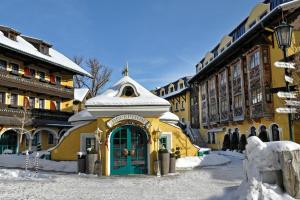 a yellow building with a green door in the snow at Hotel Pichlmayrgut in Schladming