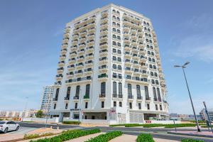 a tall white building with balconies on the side of it at Comfortable Studio with Dubailand Vibes in Dubai