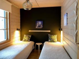 two beds in a room with a black wall at Petäjähovi in Kuusamo