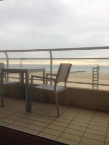 a table and chair on a balcony with the beach at Appartement Admare Middelkerke in Middelkerke